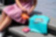 A woman in a pink floral dress opens a pouch of Jersey Jellies edibles while sitting outside—capturing the bright, playful vibe of summer snacking with infused gummies.