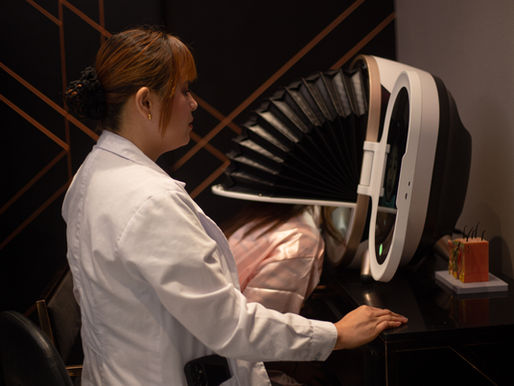 A woman wearing a white lab coat is overseeing an ongoing skin analysis procedure beside her