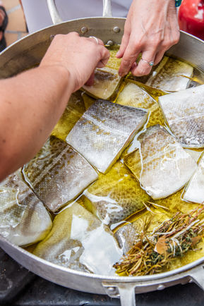 placing fish in a pan during a Catalan Cooking workshop for teams