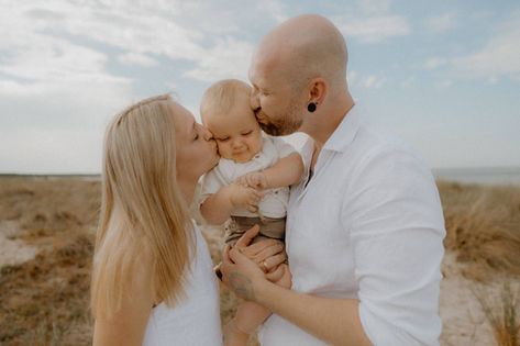 Eltern küssen ihren Sohn liebevoll bei einem Familienshooting in Lobbe. Monique ist Familienfotografin auf Mönchgut Gager auf Rügen. 