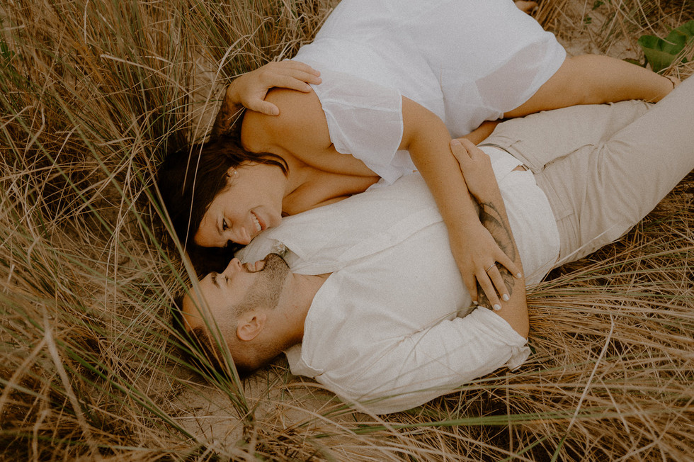 Paar liegt verliebt im Dünengras an der Ostsee. Authentische Paarshootings in Binz, Sellin, Göhren und Baabe.
