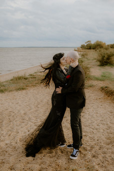 Pärchen im schwarzen Hochzeitsoutfit küsst sich leidenschaftlich auf Insel Usedom. Fotograf begleitet alternative Hochzeit auf Usedom.