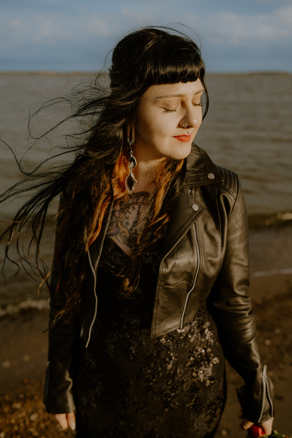 Schwarz gekleidete Braut mit Lederjacke. Begleitet von Fotografin für besondere Elopementhochzeiten an der Ostsee.