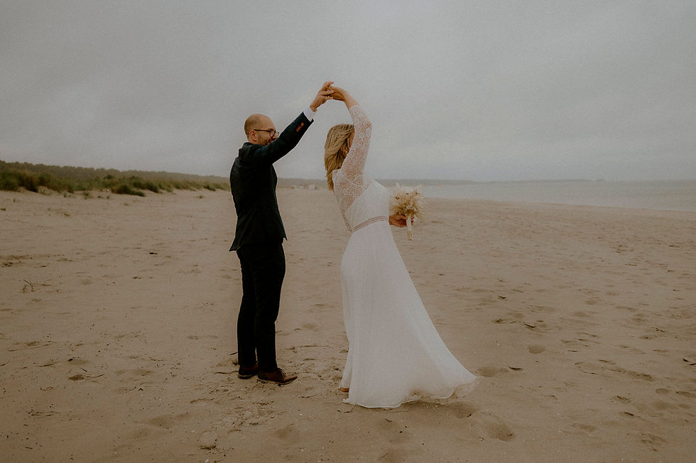 Brautpaar tanzt im Regen auf Fischlanddarss am Strand. Paarshooting bei Regen am Strand in Zingst.