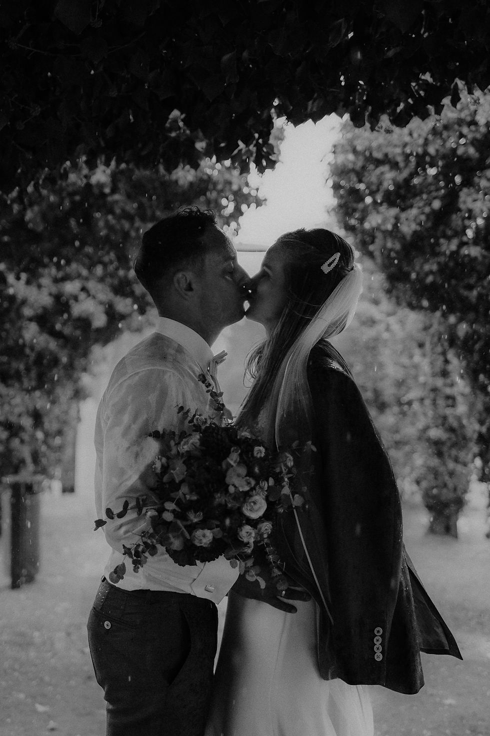 Pärchen steht bei strömenden Regen in Heringsdorf unter einem Baum und küsst sich. Hochzeitsfotografin für Regenhochzeit auf Usedom. Regen am Hochzeitstag in Ahlbeck.