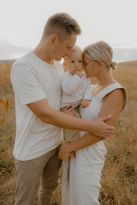 Familie steht eng zusammengekuschelt auf einer Wiese in Güstrow. Familienfotograf begleitet sie.