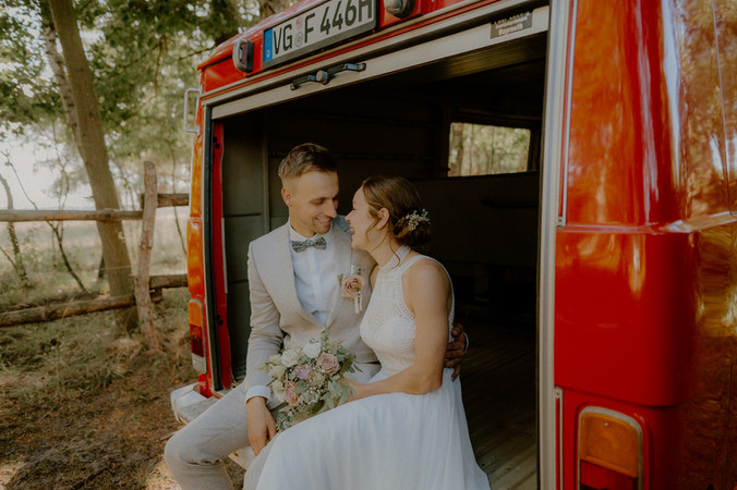 Paarshooting in einem Feuerwehrauto in der Natur bei Neubrandenburg. Pärchen genießt Zweisamkeit beim Fotoshooting. Hochzeitsfotograf in Neubrandenburg für freie Trauung im Park. 