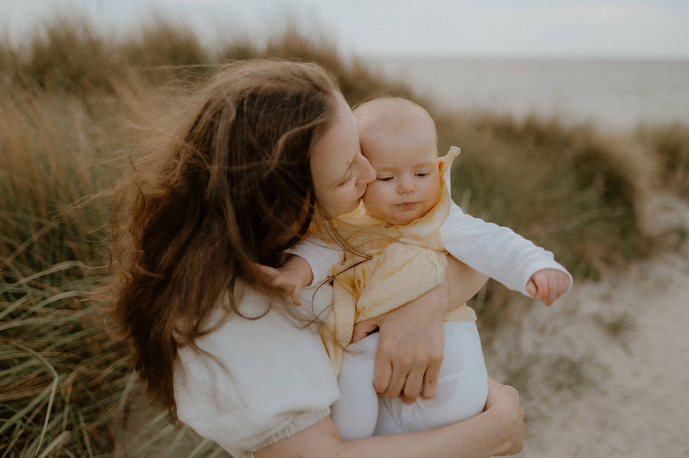 Familienfotograf in Rostock am Meer: eine Mama küsst liebevoll ihre kleine Tochter.