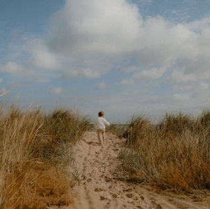 Familienshooting Baabe: kleiner Junge lĂ€uft freudig durch die DĂŒnen auf die Ostsee zu.