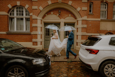 Regenhochzeit in Lübeck. Heiraten im Standesamt. Paarshooting mit Regenschirme in der Stadt. Hochzeitsfotograf in Schleswig-Holstein.