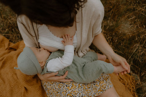 Gefühlvolle Stillfotografie in Gehlsdorf bei Rostock. Eine Mama still ihre Tochter auf einer wilden Wiese.