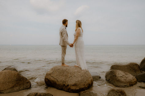 Hochzeitsfotograf für Trauung in Binz: Brautpaar genießt beim Paarshooting einen Moment der Ruhe - stehen auf einem Stein und genießen den Ausblick auf die Ostsee.