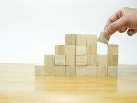 Wooden blocks stacked in ascending steps, representing layered tax brackets