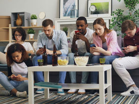Group of people sitting together all looking at their phones, ignoring each other