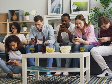 Group of people sitting together all looking at their phones, ignoring each other