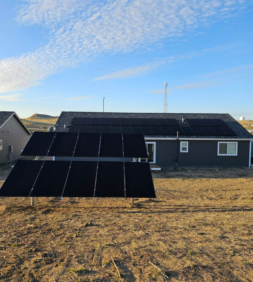 Solar panels on a home with adjacent ground-mounted array