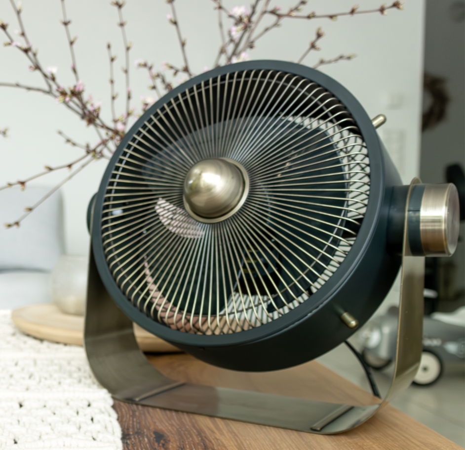 Stylish retro-style table fan with brass accents placed on a wooden table in a modern living room.