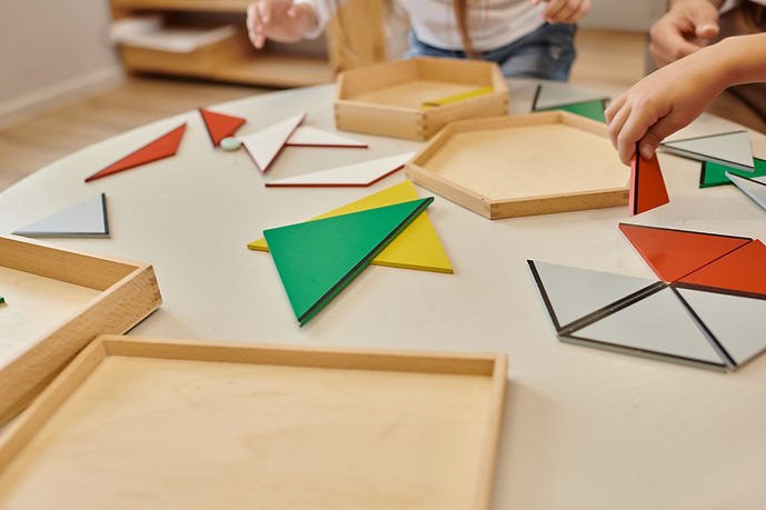 cropped view of teacher and kids playing with triangles on table in montessori school.jpg