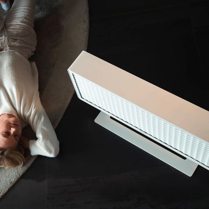 Modernes Bitcoin-Heizgerät in einem Wohnbereich, daneben liegt eine Person entspannt auf dem Boden.