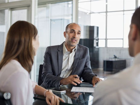 professional advisor in a suit jacket with clients who have their backs to camera used on a blog about the LMI waiver for professionals