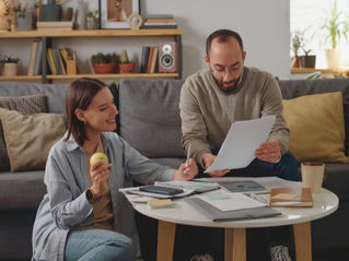 a couple in a living room reviewing documents on a table and making notes used on a blog about debt recycling strategy vs borrowing for an investment property.