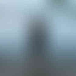 Girl stands on a lakeside path, forming a heart with her hands, overlooking a dome across the water at dusk. Tree branches above.