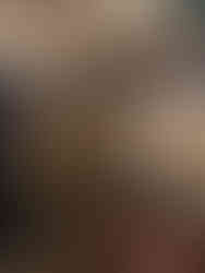 Antique shop with vases, a mirror showing a woman holding a phone, ornate lamps, and small elephant figurines on a red table. Warm lighting.