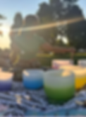 Woman playing crystal singing bowls outdoors at sunset