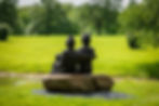 Bronze family statue sitting on a rock in a green park