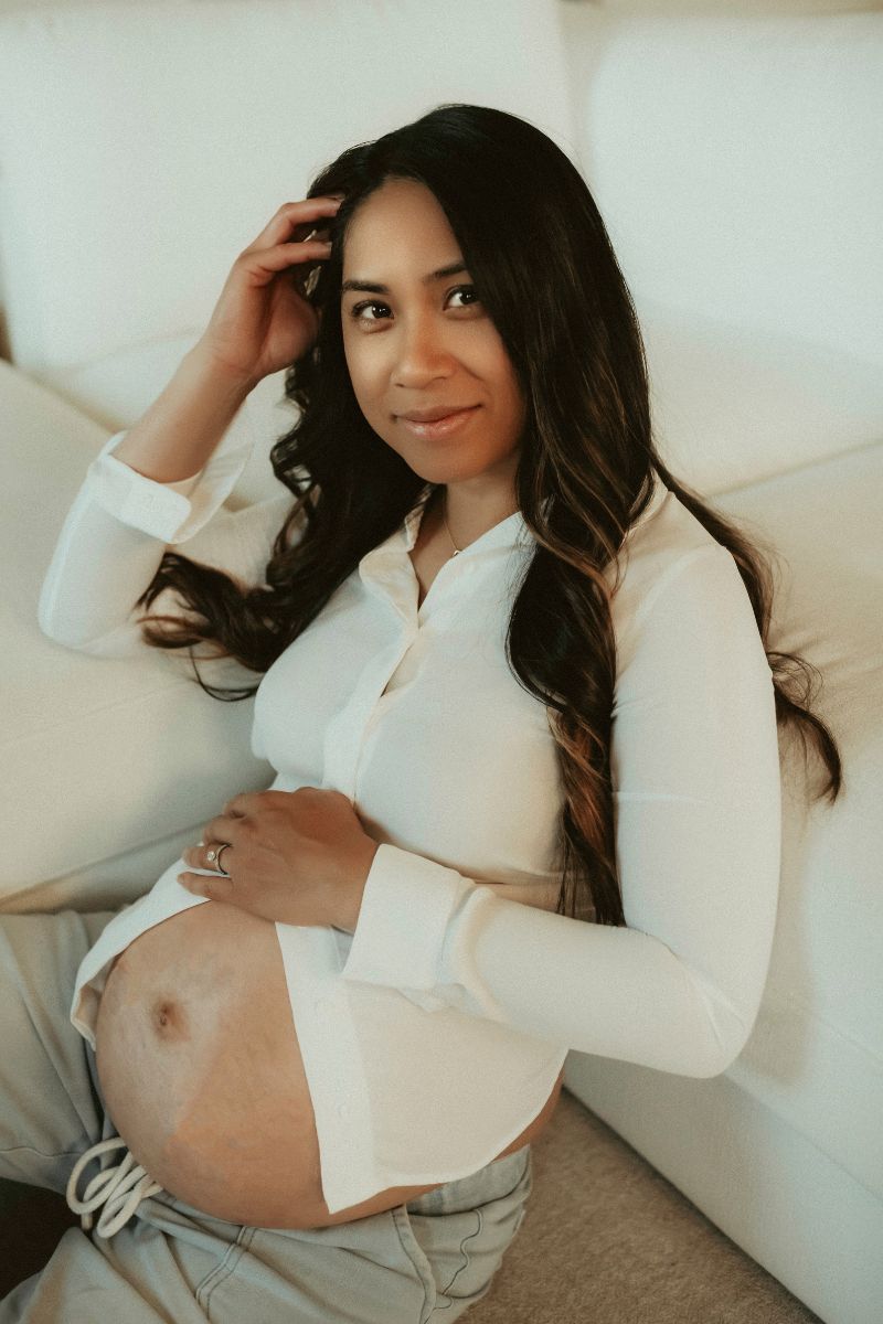 Expecting mom in jeans and white top posing for photo