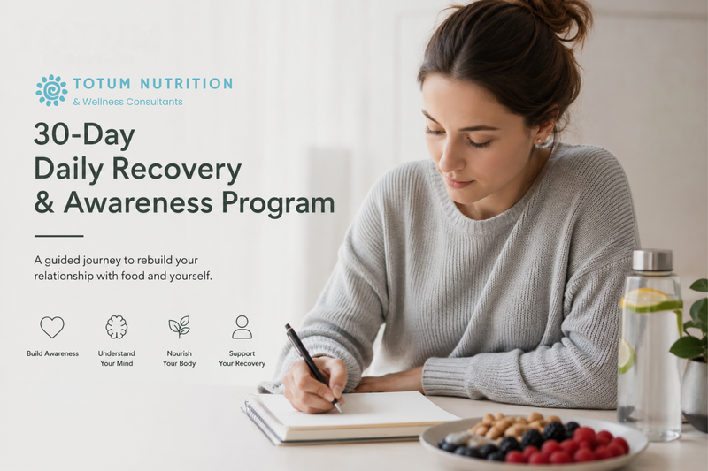 Young woman writing in a journal at a table with berries, nuts, and a water bottle in a bright, peaceful setting. The image promotes Totum Nutrition's 30-Day Daily Recovery & Awareness Program for individuals working on eating disorder recovery and building a healthier relationship with food.