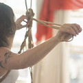Mulher fazendo linha de suspensão para shibari em estúdio sob a luz do dia