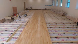 Junckers sports flooring being installed in a school hall, showcasing durable and high-performance timber surface.