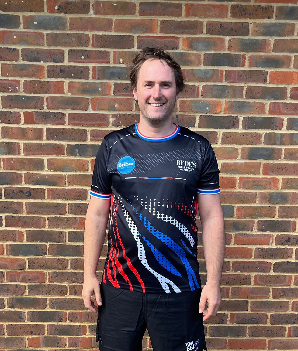 A man in a table tennis jersey in front of a brick wall
