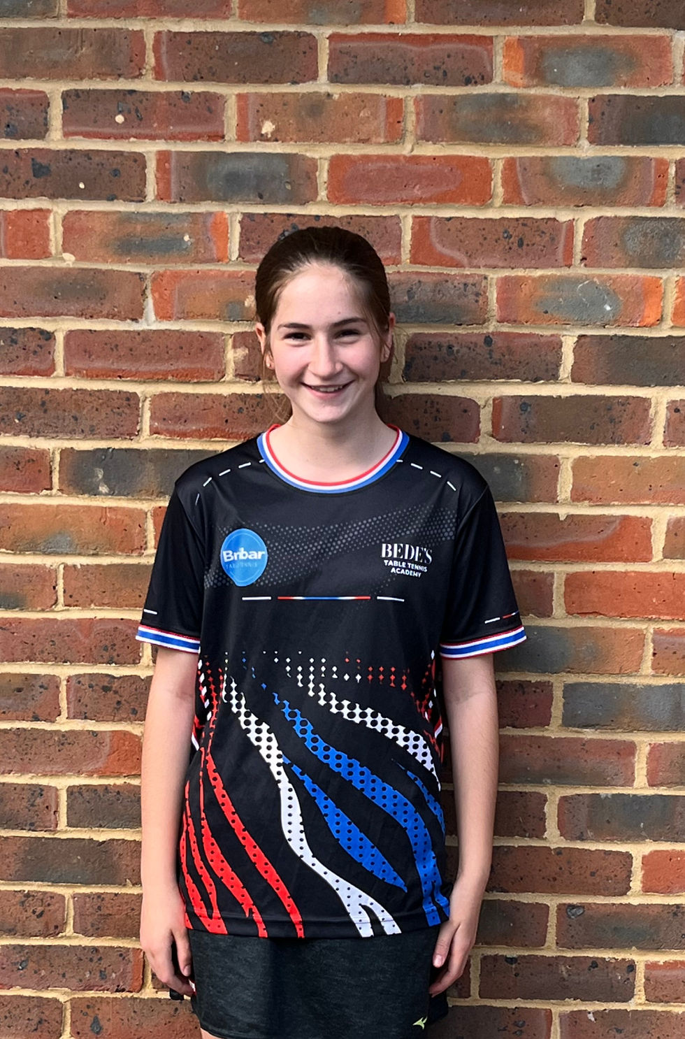 Young female table tennis player in team jersey.
