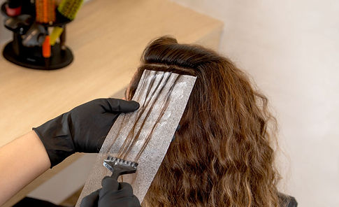 Eine Frau lässt sich ihre Haare strähnen beim Friseur
