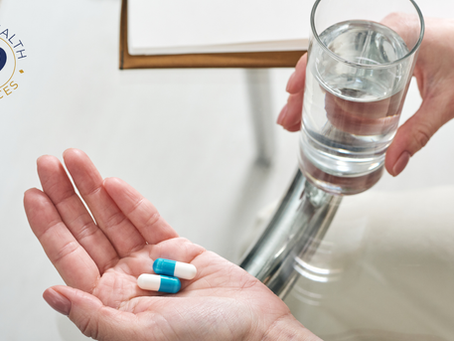 Close-up of an older adult holding medication capsules while receiving a glass of water, representing safe medication management and medication reminders for seniors at home.