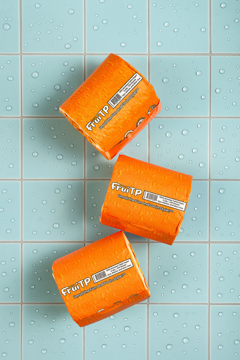 Orange FruiTP toilet paper rolls styled on blue tile background | Commapix Studio