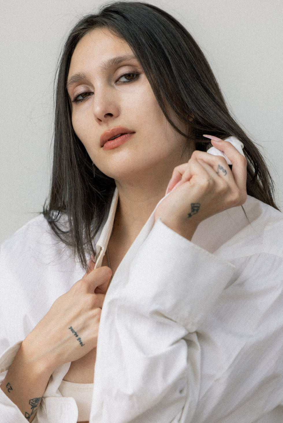 Commapix natural light portrait, Los Angeles — close-up of a model in an open white shirt, hand near her face.