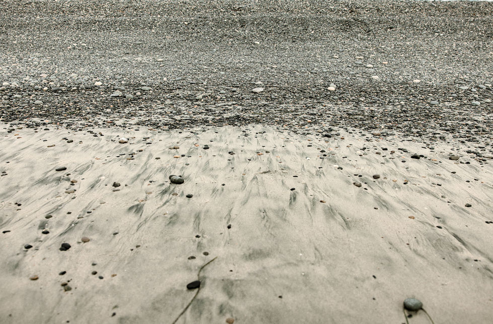 Wet sand and pebbles stretching to the sea