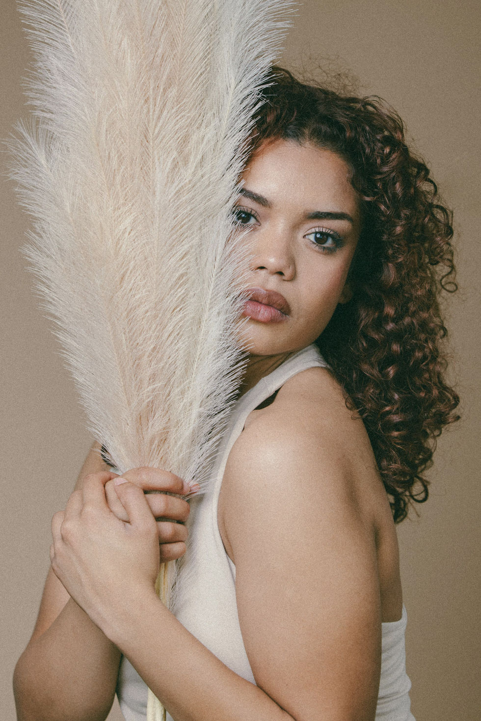 Conceptual beauty portrait by Commapix in DTLA — model holding feathery pampas grass beside her face