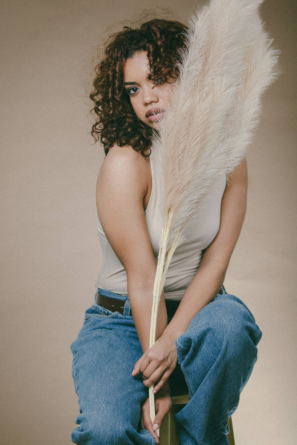 Commapix Conceptual Portrait Photography, DTLA — seated model holding a tall pampas plume in soft studio light.