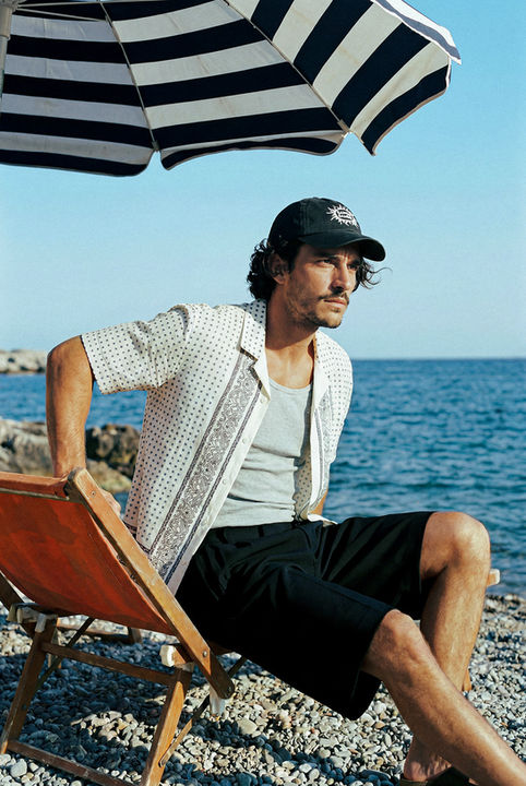 Image générée par IA : mannequin en chemise à carreaux, casquette, face à la mer.