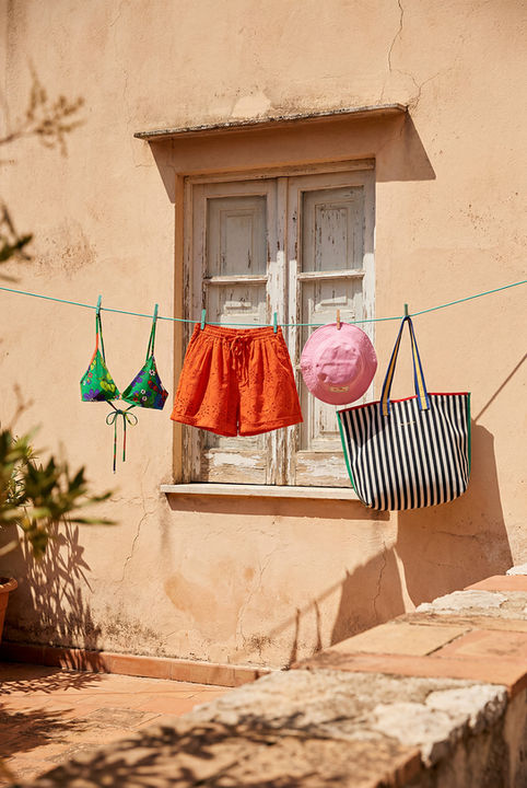 Image générée par IA : maillot vert, short orange et sac rayé suspendus sur un fil.