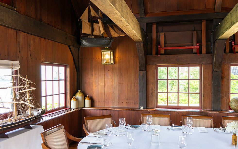 Gedekte tafels in een zaal met houten lambrisering en een scheepsmodel bij D'Swarte Walvis, Zaanse Schans