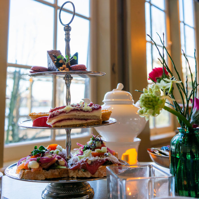 Tiered stand with sandwiches, cakes, and tea