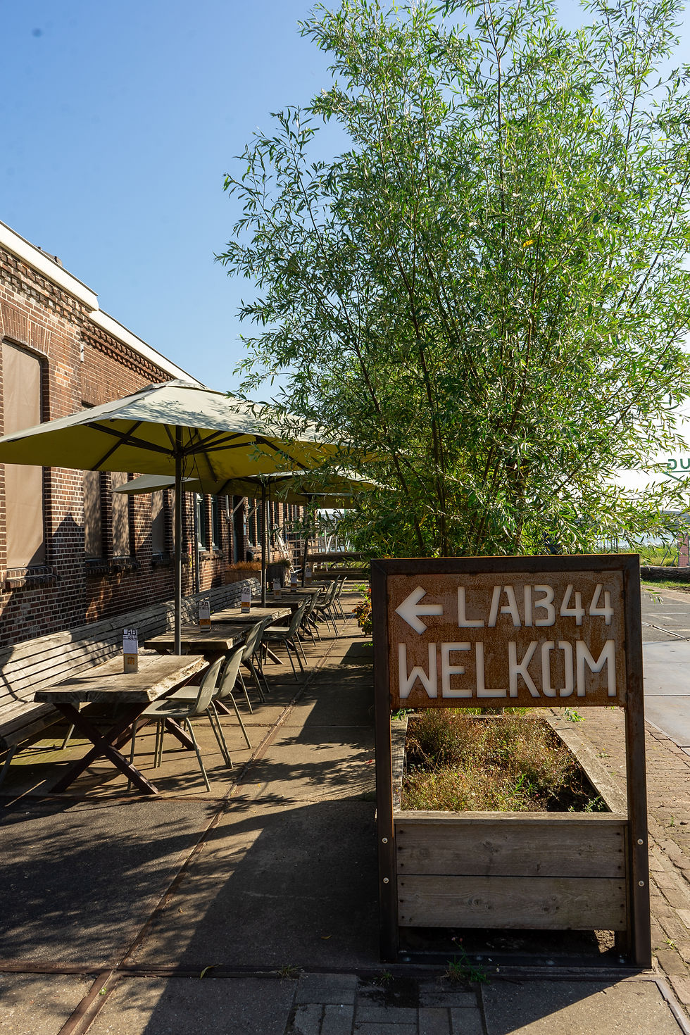 Terras met welkomstbord van LAB-44 in de zon