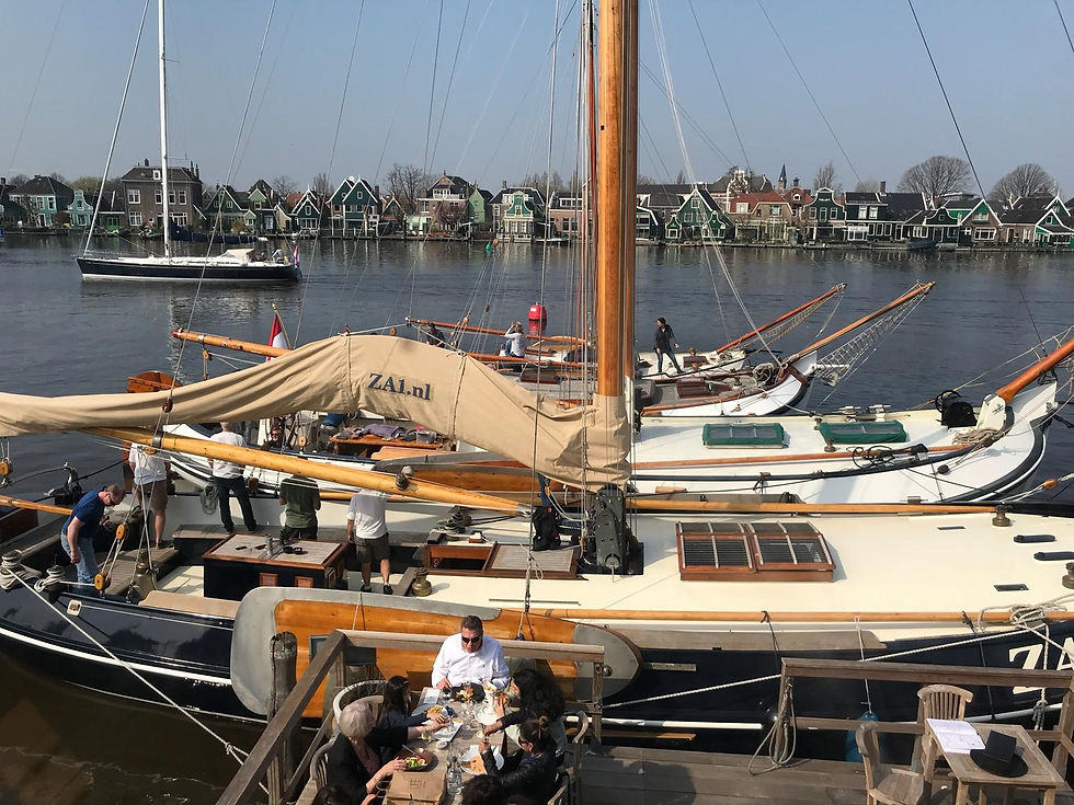 Traditionele zeilboten afgemeerd aan de rivier de Zaan bij D'Swarte Walvis, Zaanse Schans