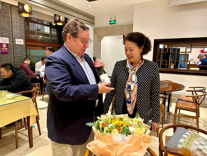 Global Business Journalism co-director Rick Dunham presents Rose Li with a bottle of wine at a retirement dinner at Tsinghua University.