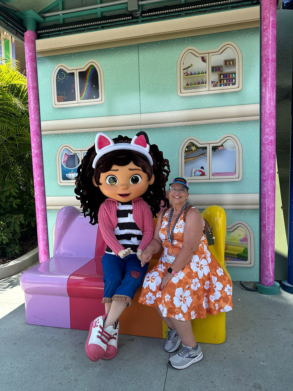 woman sitting on couch with the character Gabby at the theme park.